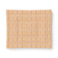 A rectangular fabric placemat with a repeating ornate damask pattern in soft peach, orange, and pale pink tones, shown on a clean white background.