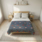 A neatly made bed in a bright bedroom, featuring a navy blue floral quilt with red and peach flowers, white pillows and top sheet, a light wood bed frame, two matching nightstands, and a woven rug.