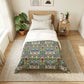 A neatly made bed in a bright, modern bedroom featuring a William Morris-style floral patterned comforter. The bedding includes white pillows and a white top sheet, with the patterned comforter draped over the lower half.