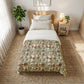 Bedroom with a floral-patterned comforter on a bed, nightstand, and plant.