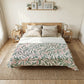 Bedroom with a bed featuring a leaf-patterned comforter, two nightstands, and framed pictures on the wall.