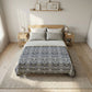 Bedroom with a bed featuring a patterned duvet cover, nightstands, and framed pictures on a shelf.