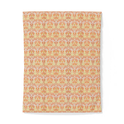 A rectangular textile item, likely a towel or blanket, featuring a repeating ornate damask-style pattern in warm orange, peach, and pale yellow tones on a light background.