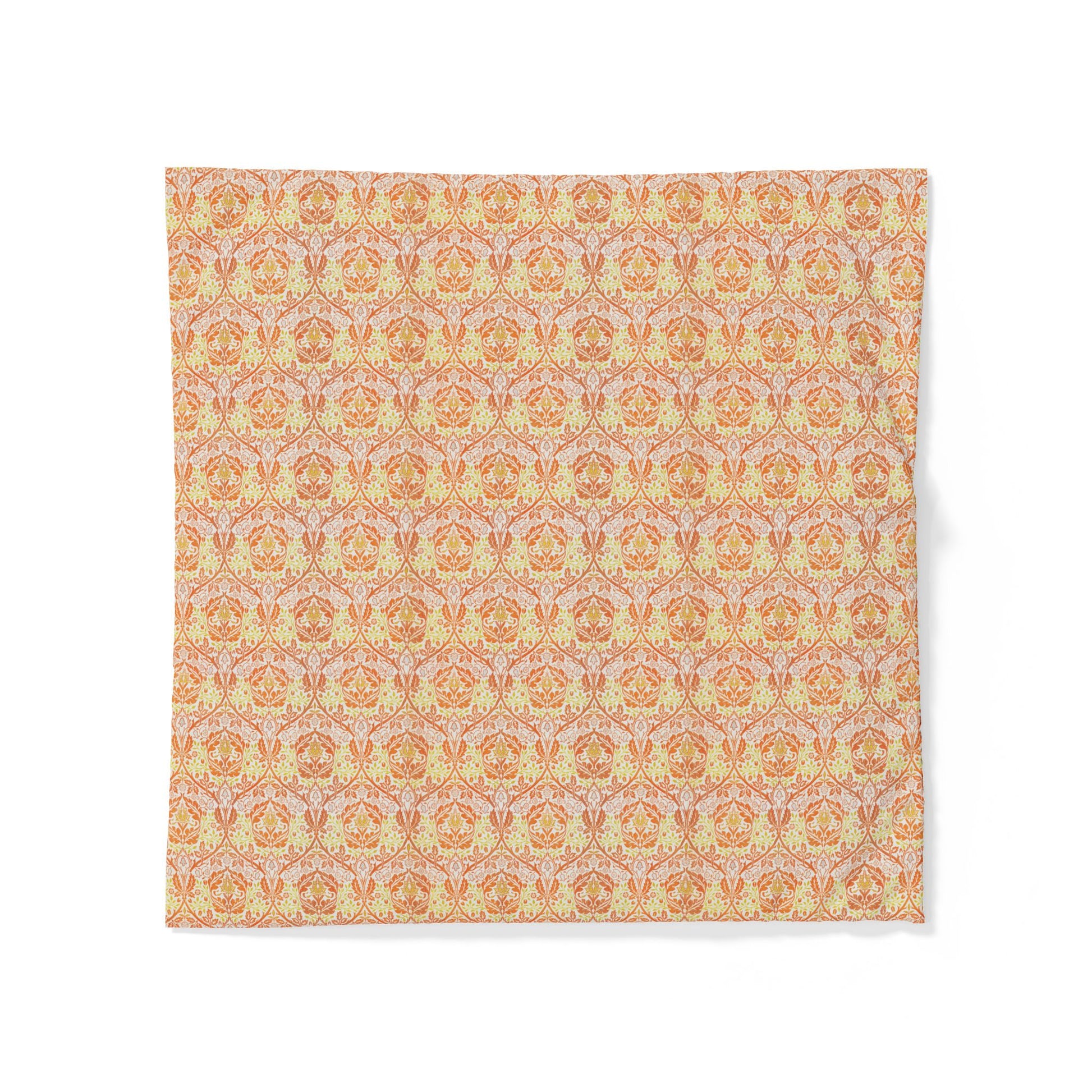 A square fabric napkin or placemat featuring an intricate repeating damask pattern in warm tones of orange, yellow, and soft pink on a white background.