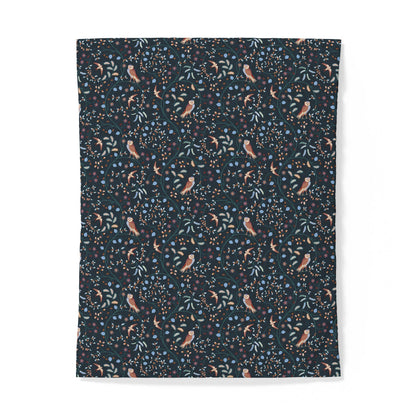 A rectangular fabric item, likely a blanket or throw, featuring a dense all-over print of small birds, leaves, and dots on a dark navy background, shown against a plain white background.