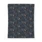 A rectangular fabric item, likely a blanket or tapestry, featuring a dense botanical and bird pattern on a dark navy background. The pattern includes small peach-colored birds, light blue flowers, and green leaves.