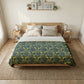 Bedroom with a bed featuring a green and yellow patterned duvet, two nightstands with lamps, and framed pictures on the wall.