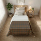 Bedroom with a bed featuring a patterned comforter, nightstand, and plant.