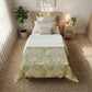 Bedroom with a bed featuring a green and white patterned comforter, nightstand, and plants.