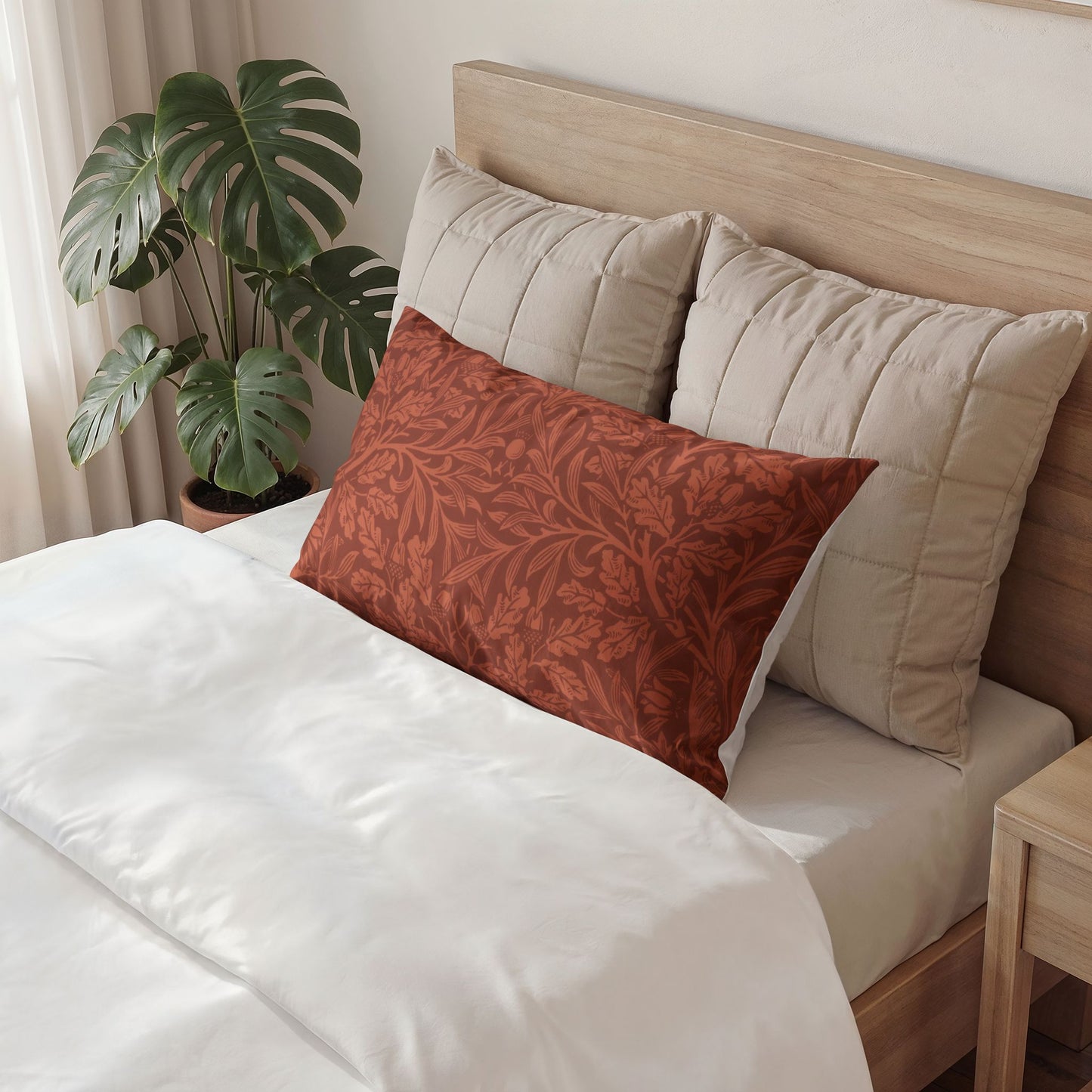 Bed with beige pillows and a red patterned pillow, next to a plant and wooden nightstand.