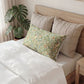 Bed with decorative pillows and a plant in the background