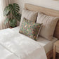 Neatly made bed with decorative pillows and a plant in the background