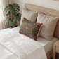 Neatly made bed with decorative pillows and a plant in the background