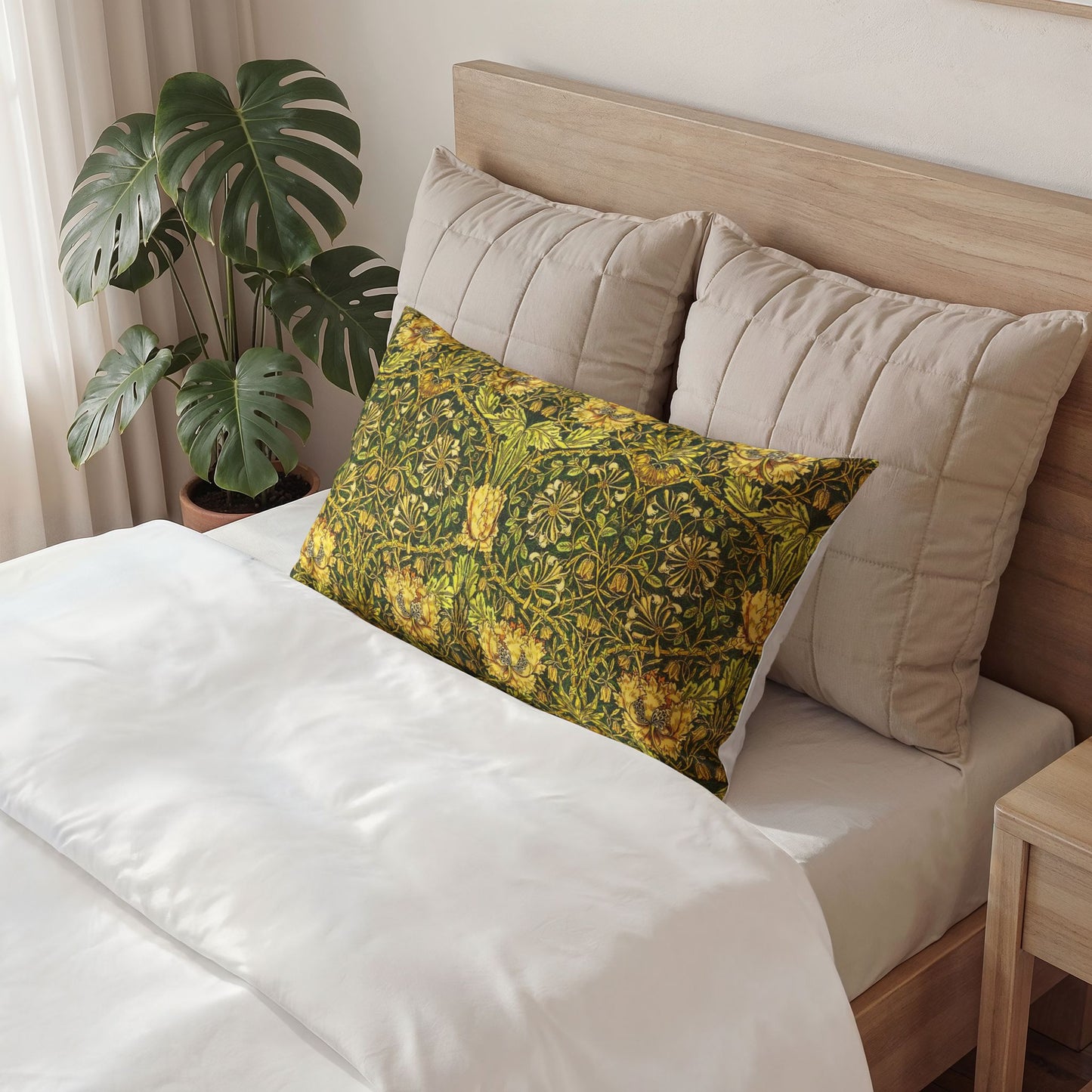 Bed with floral pillow and beige cushions, plant in the background