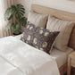Neatly made bed with decorative pillows and a plant in the background