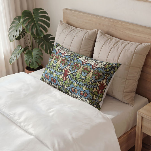 A decorative rectangular lumbar pillow with a colorful floral pattern in blue, green, and red, styled on a bed with beige pillows and white bedding in a bedroom setting.