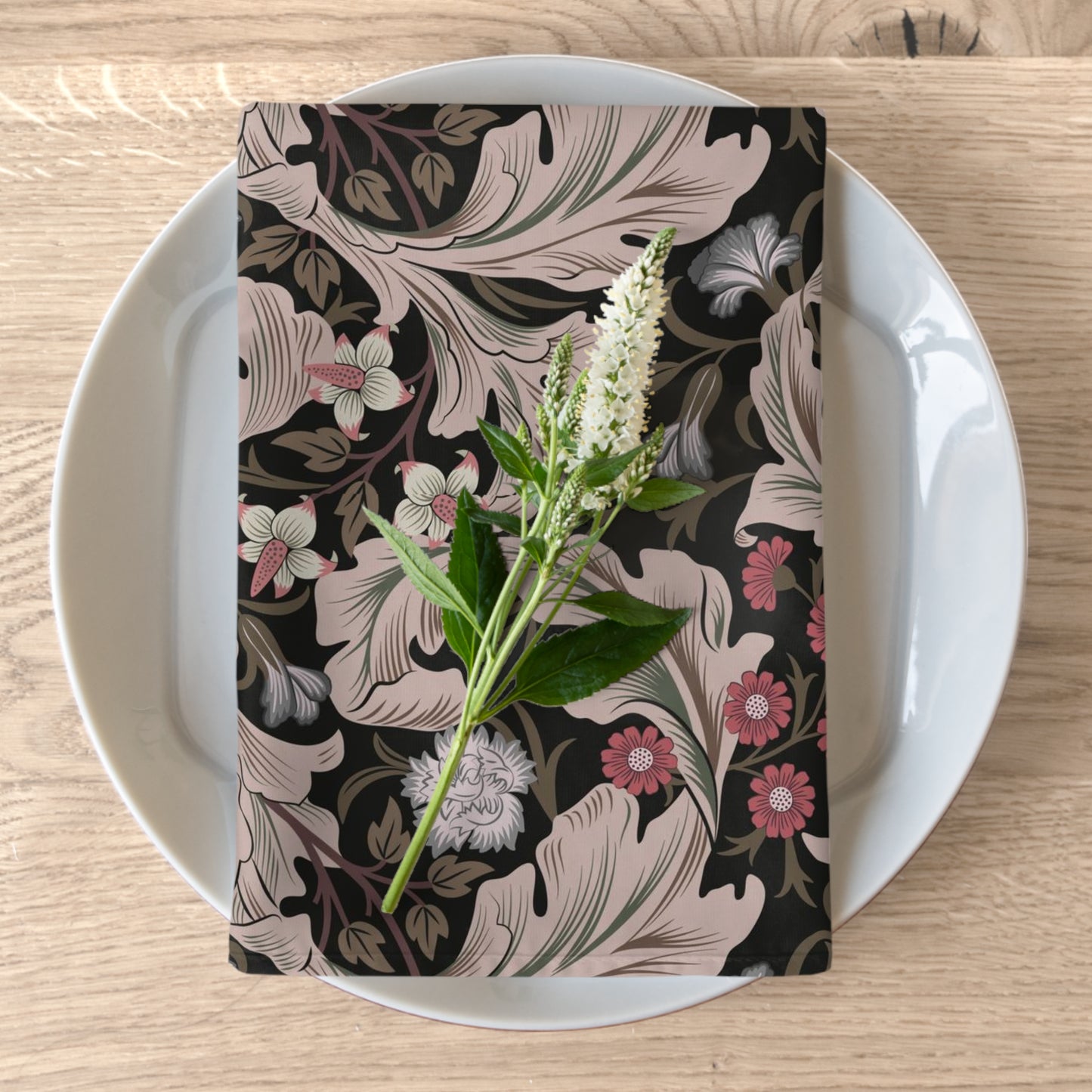 A floral patterned cotton twill napkin inspired by William Morris, displayed on a plate with a piece of floral decor.