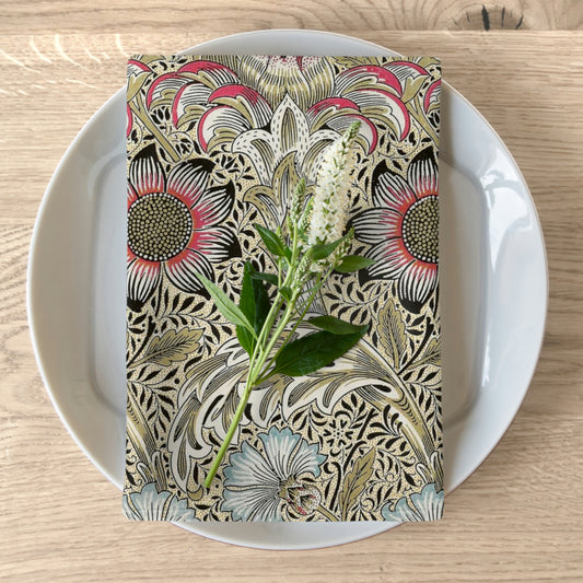 A floral patterned cotton twill napkin inspired by William Morris, displayed on a plate with a piece of floral decor.