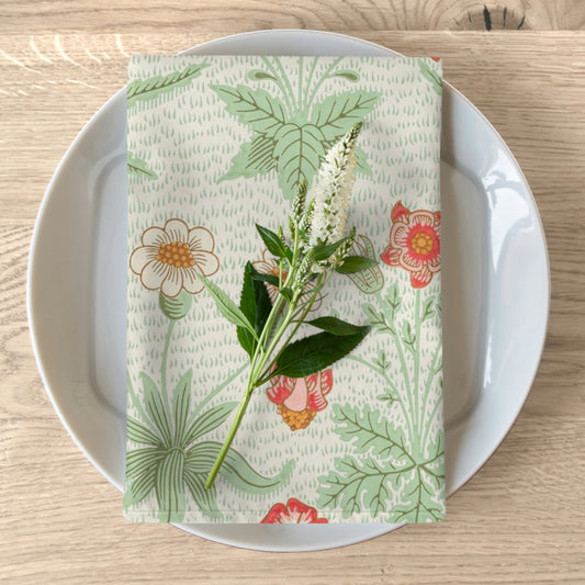 A floral patterned cotton twill napkin inspired by William Morris, displayed on a plate with a piece of floral decor.