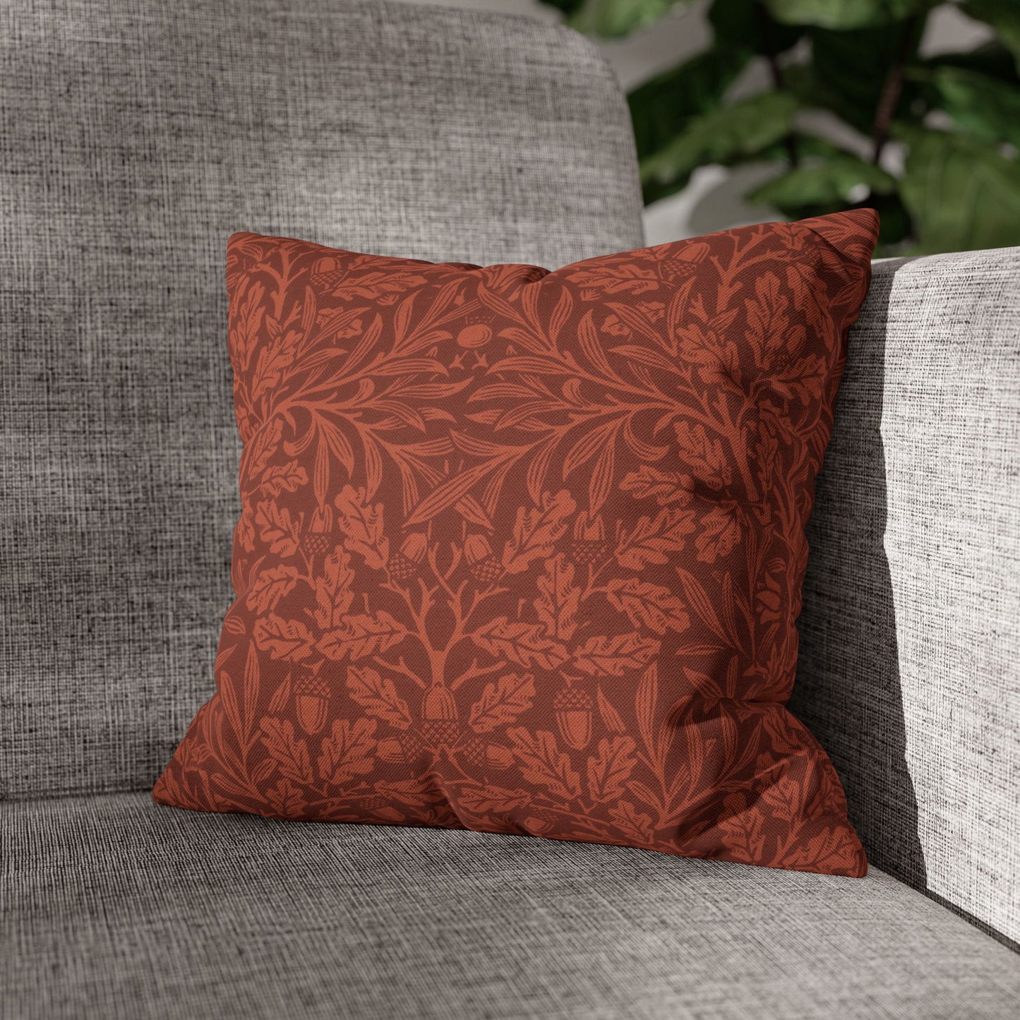 Red patterned pillow on a gray sofa with a blurred green plant in the background