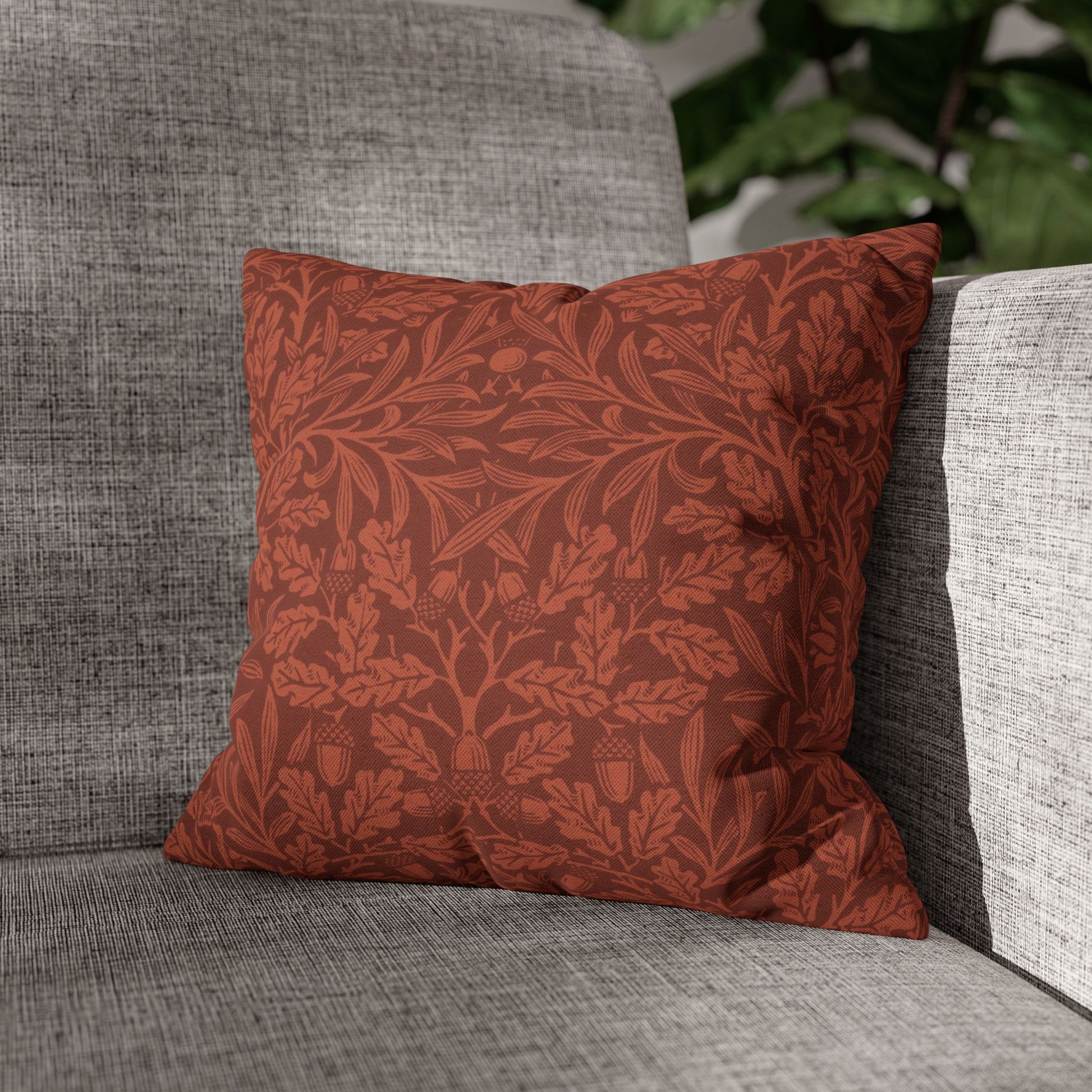 Red patterned pillow on a gray sofa with a blurred green plant in the background