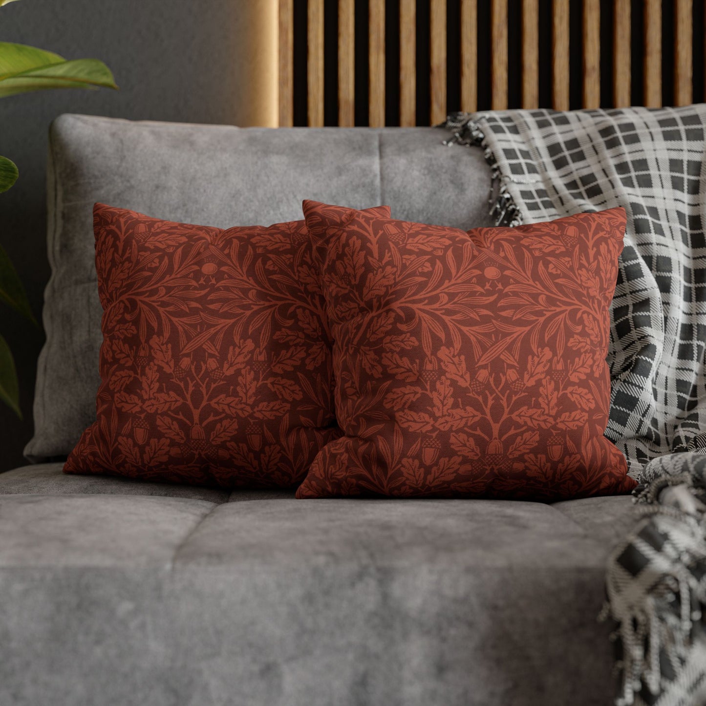 Two red patterned pillows on a gray sofa with a wooden headboard in the background.