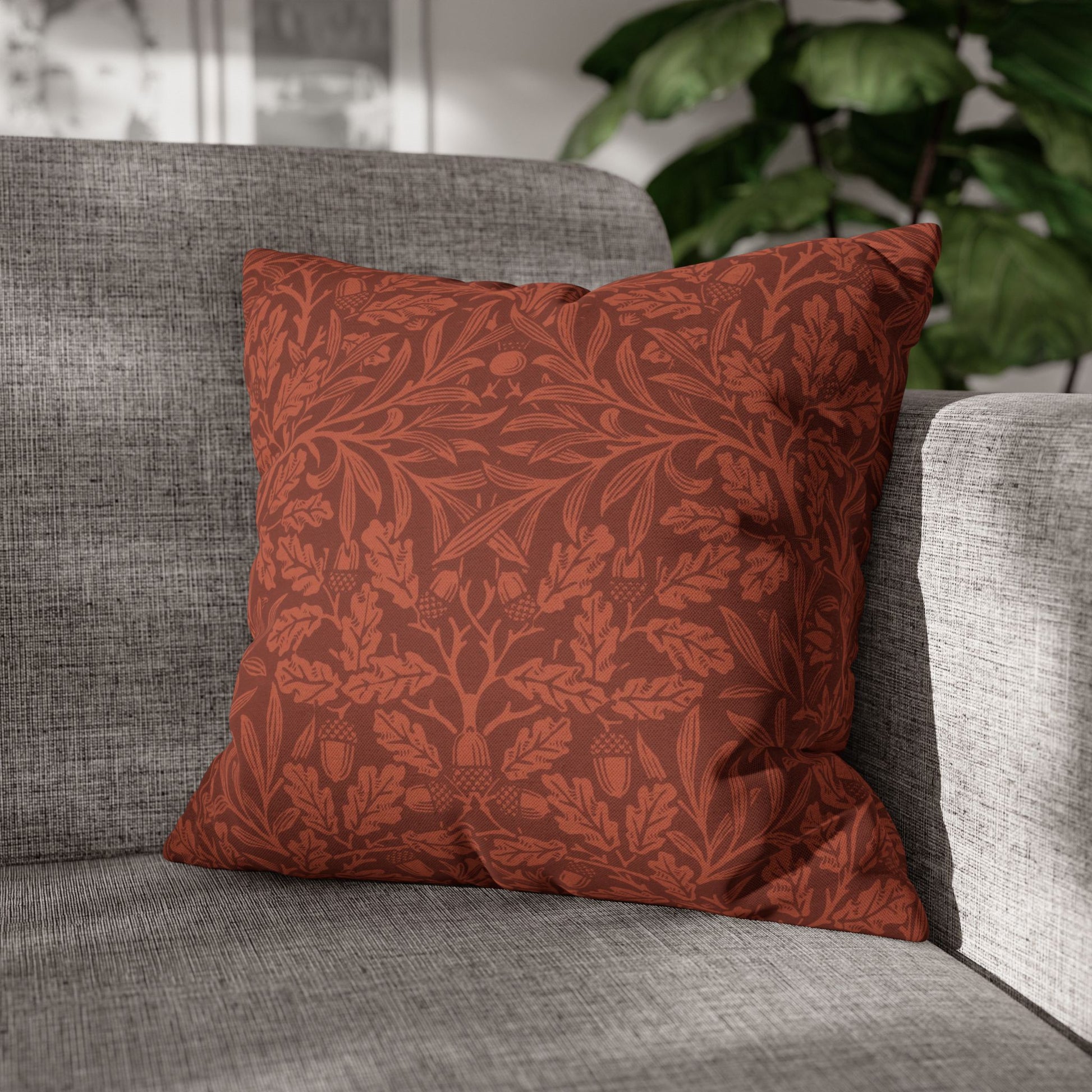 Red patterned pillow on a gray sofa with a blurred plant in the background