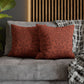 Red patterned pillows on a gray sofa with a wooden headboard in the background