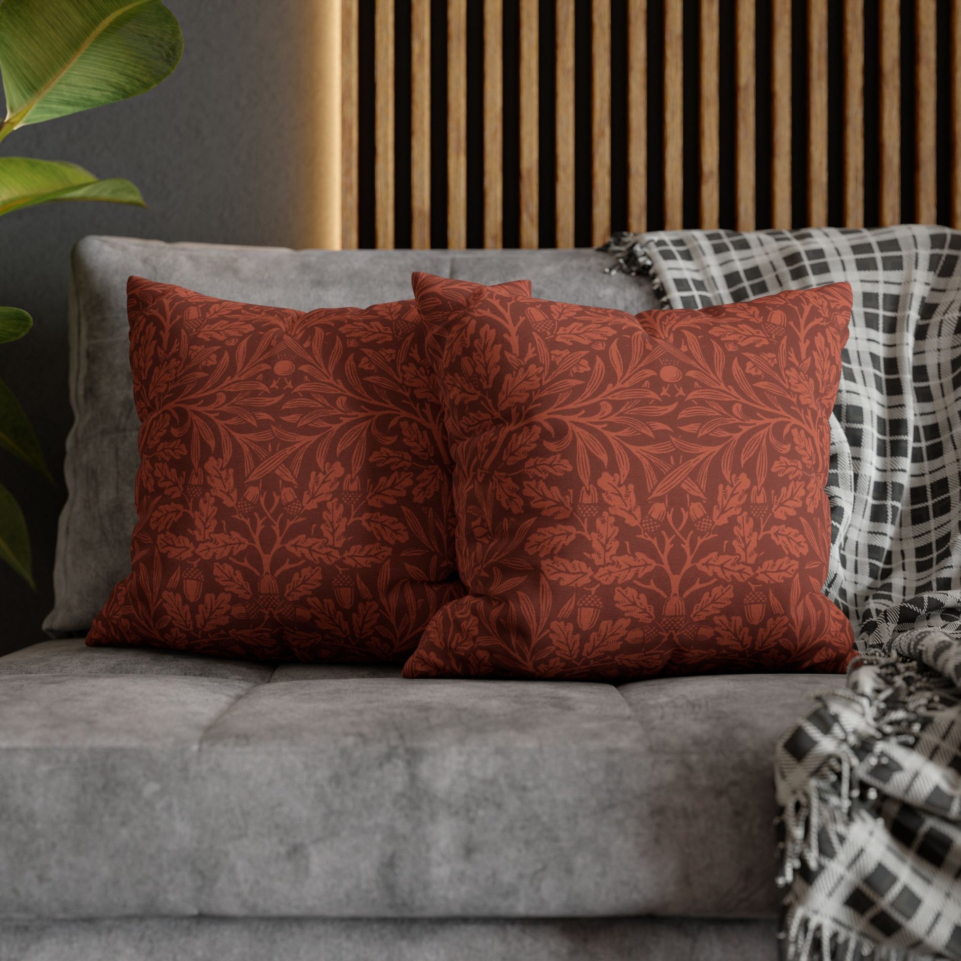 Red patterned pillows on a gray sofa with a wooden headboard in the background