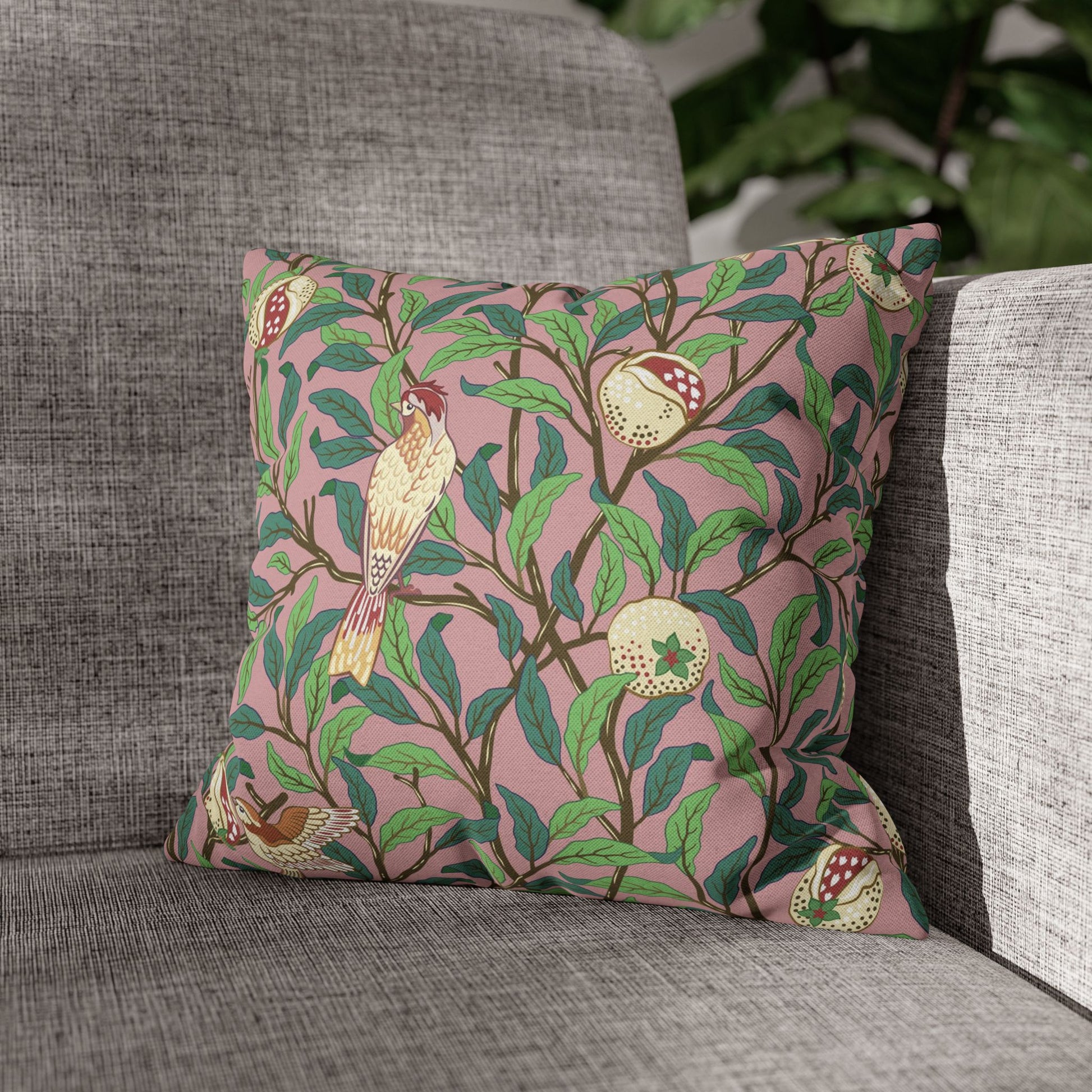Decorative pillow with bird and leaf pattern on a gray sofa