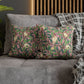 Two patterned cushions on a gray sofa with a wooden headboard in the background.