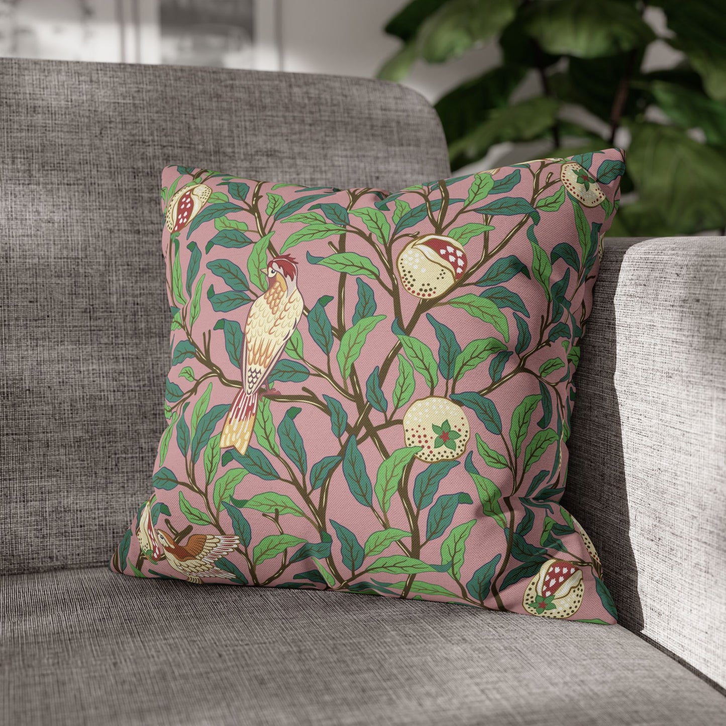 Decorative pillow with bird and pomegranate pattern on a gray sofa