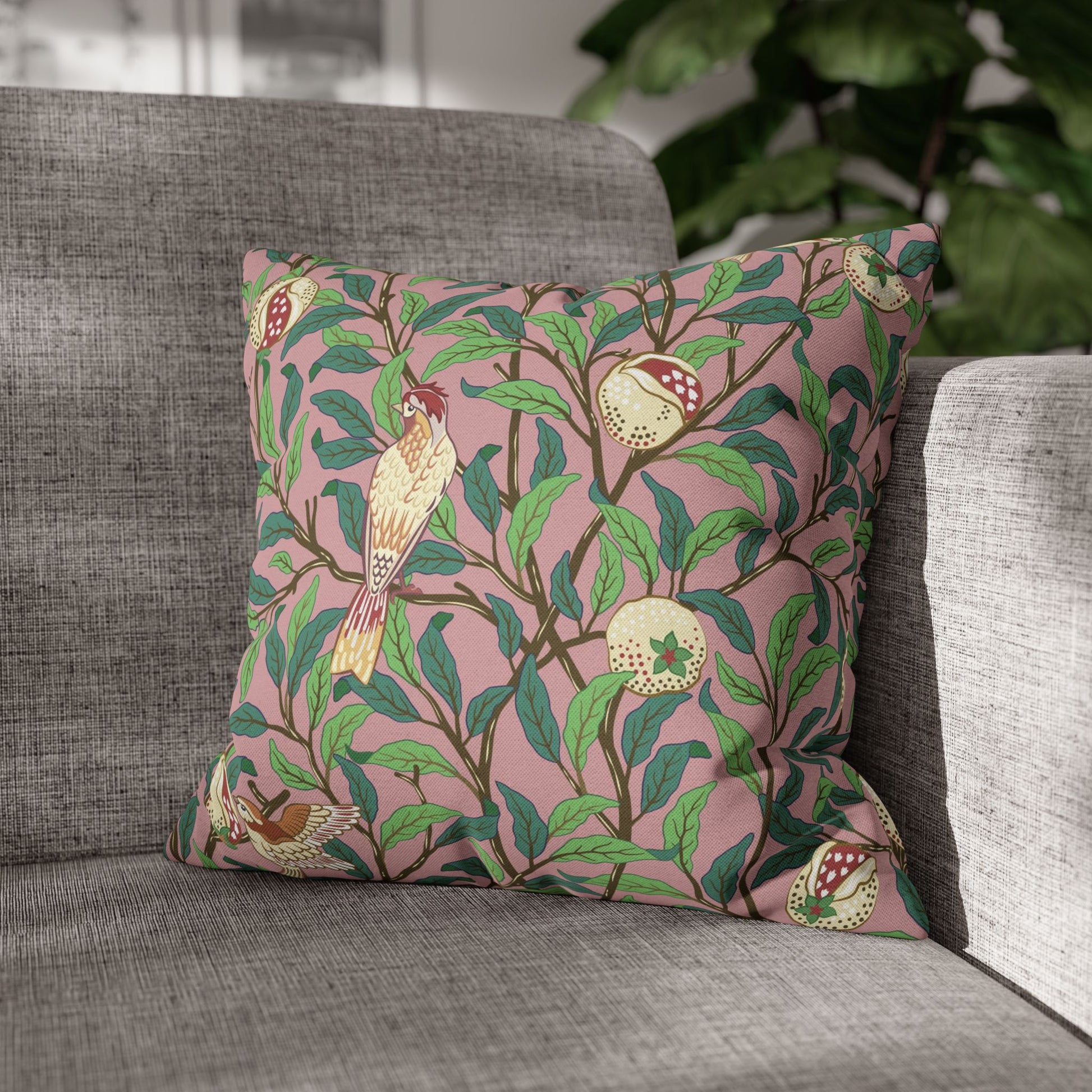 Decorative pillow with bird and pomegranate pattern on a gray sofa