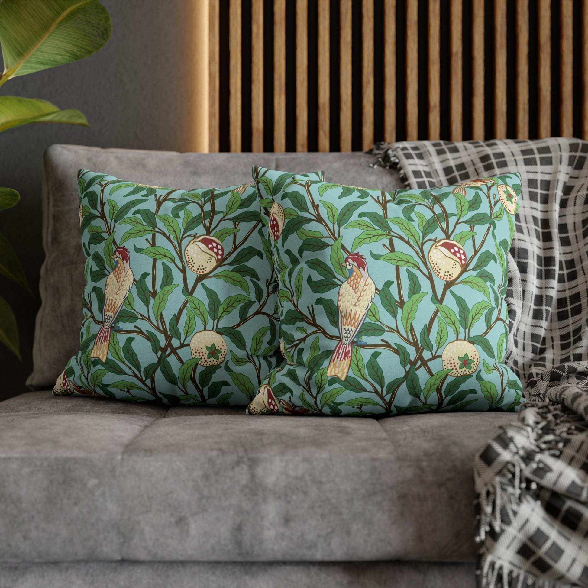Decorative pillows with bird and leaf pattern on a gray sofa.