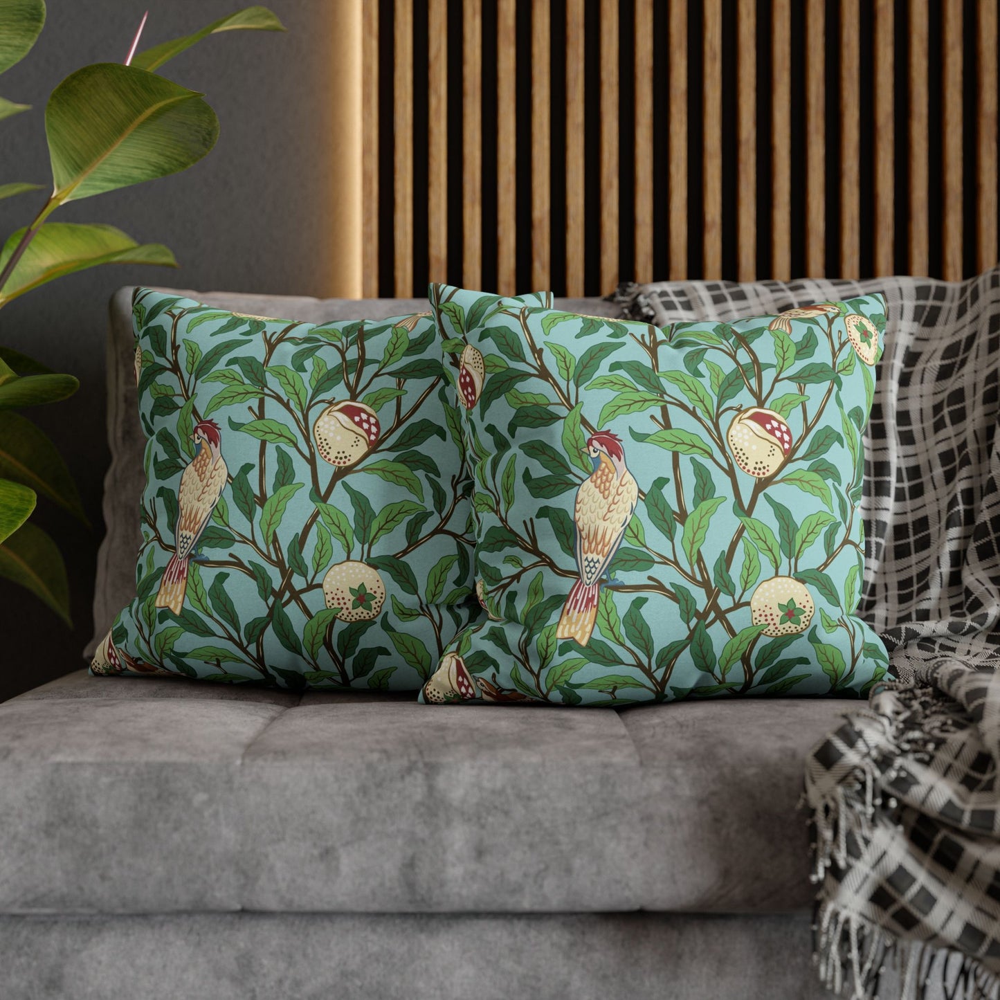 Decorative pillows with bird and leaf pattern on a gray sofa.