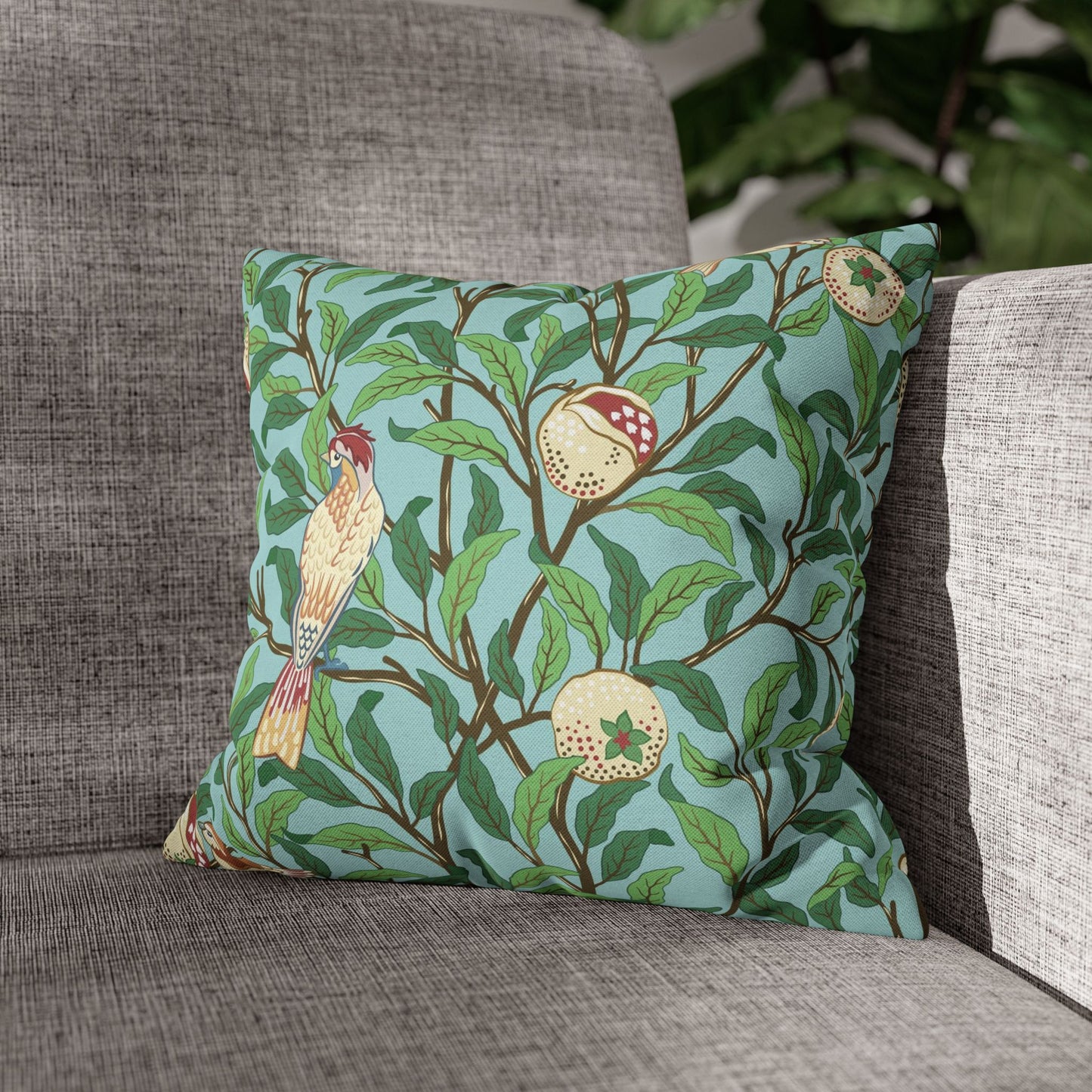 Decorative pillow with bird and fruit pattern on a gray sofa