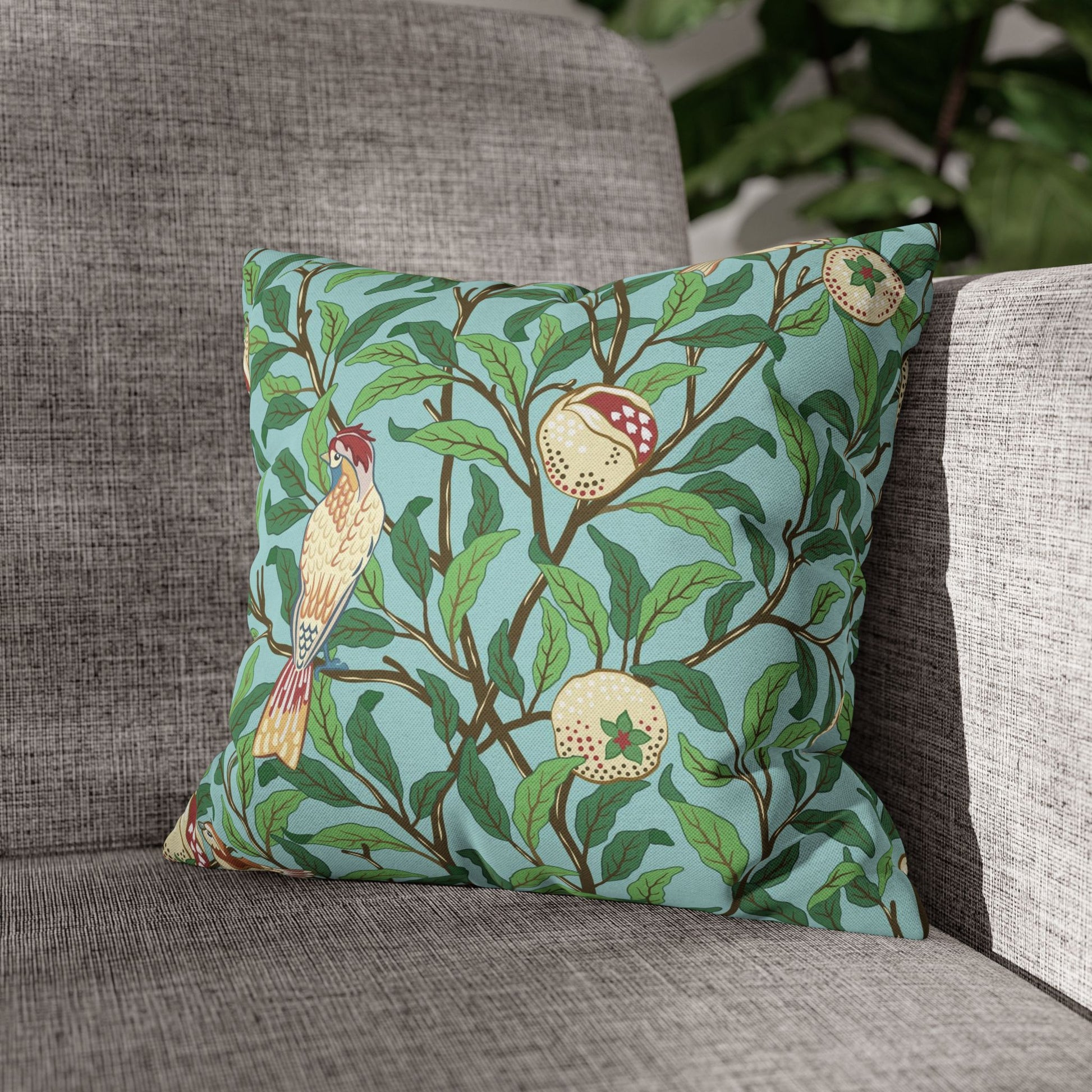 Decorative pillow with bird and fruit pattern on a gray sofa