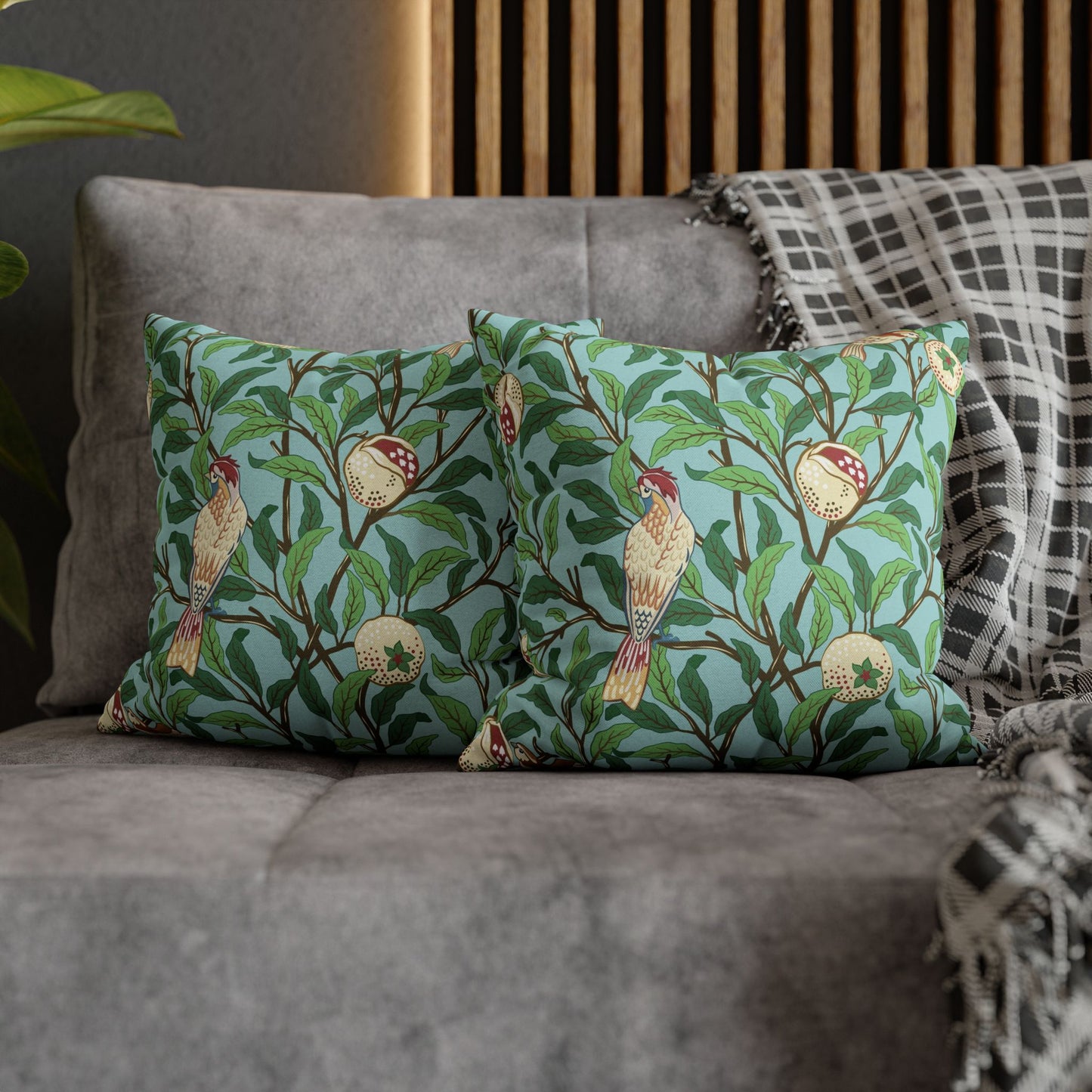 Two decorative pillows with bird and leaf pattern on a gray sofa.