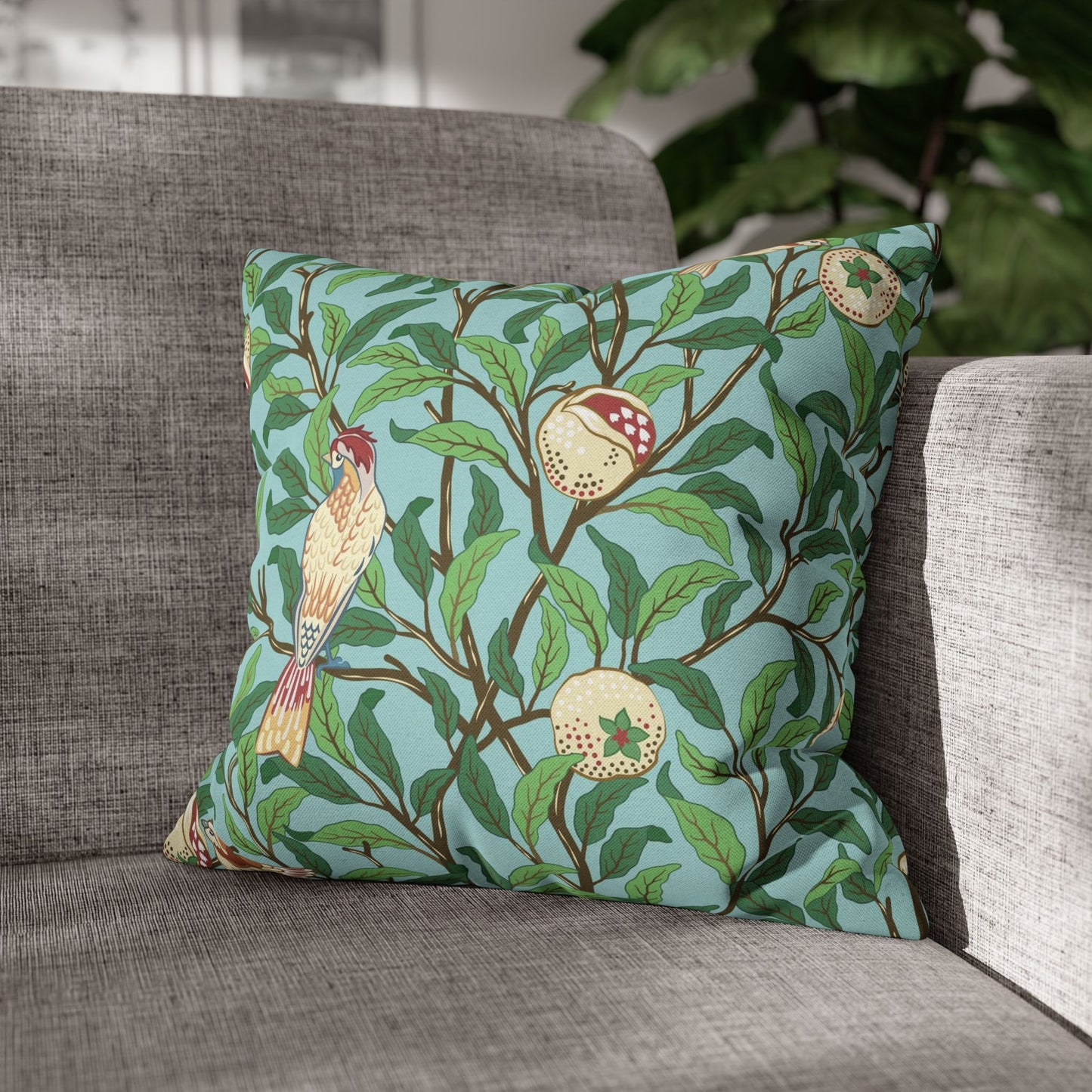 Decorative pillow with a bird and fruit pattern on a gray sofa