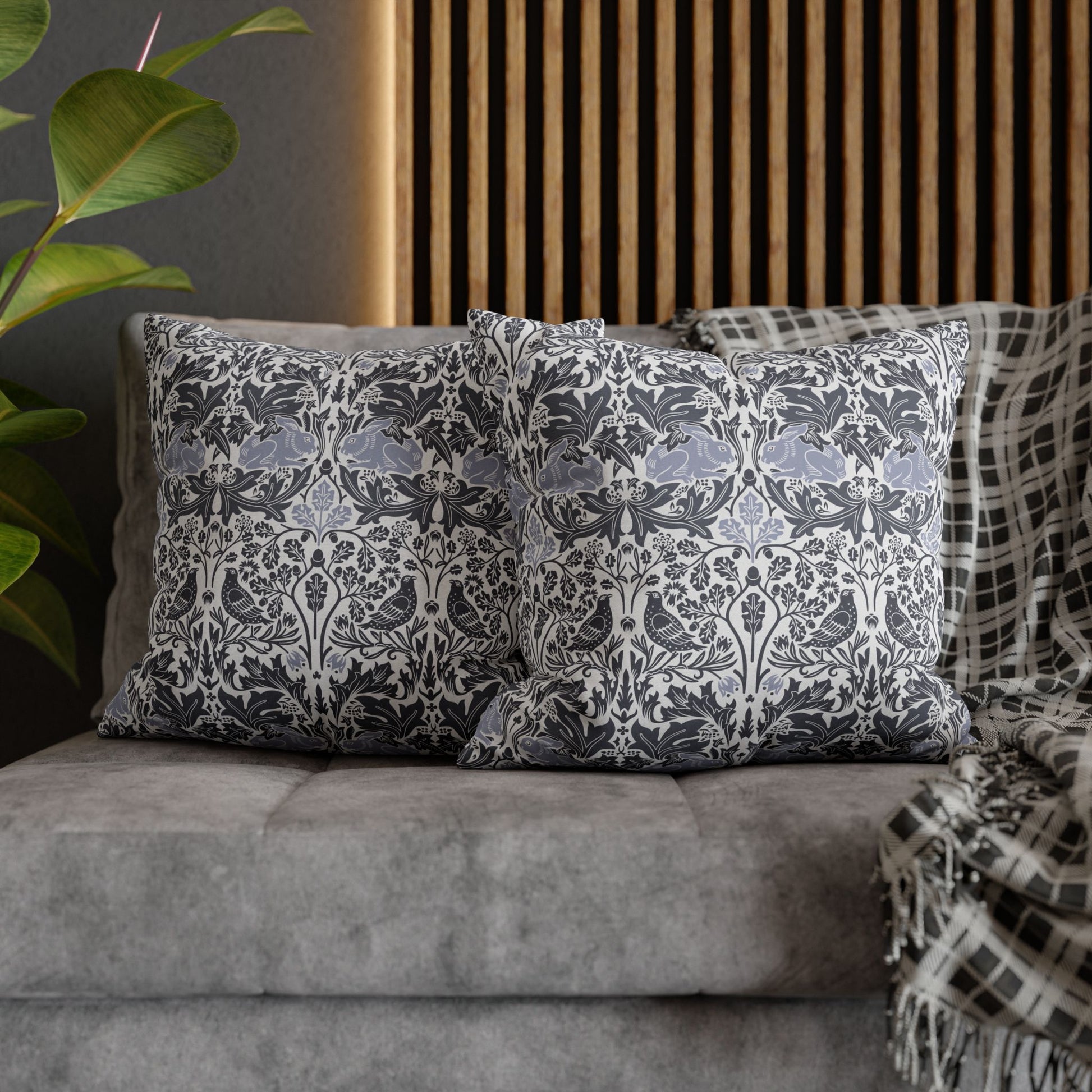 Decorative pillows with a floral pattern on a gray sofa next to a plant.