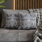Decorative pillows on a gray sofa with a wooden headboard in the background