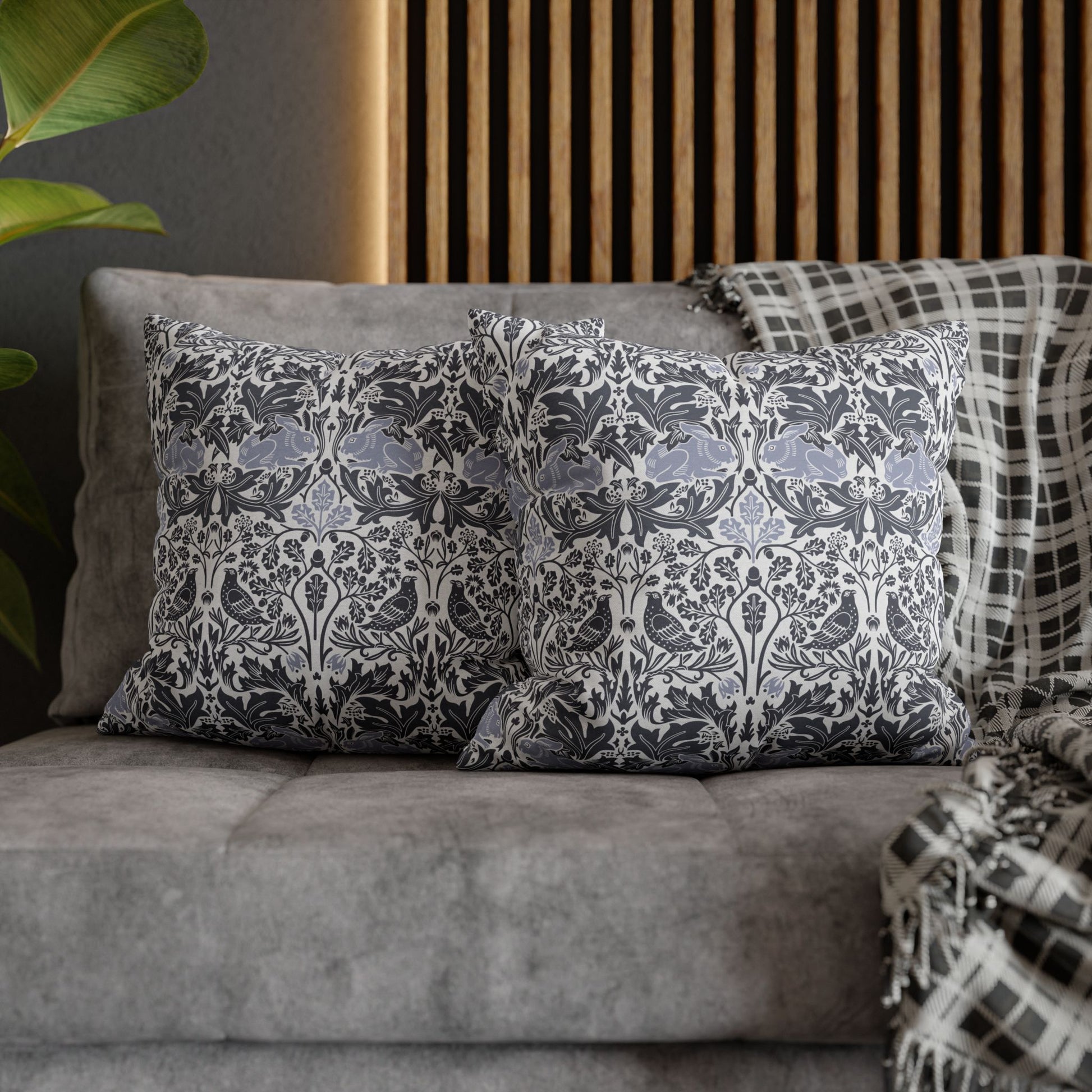 Decorative pillows with a floral pattern on a gray sofa against a wooden panel wall.