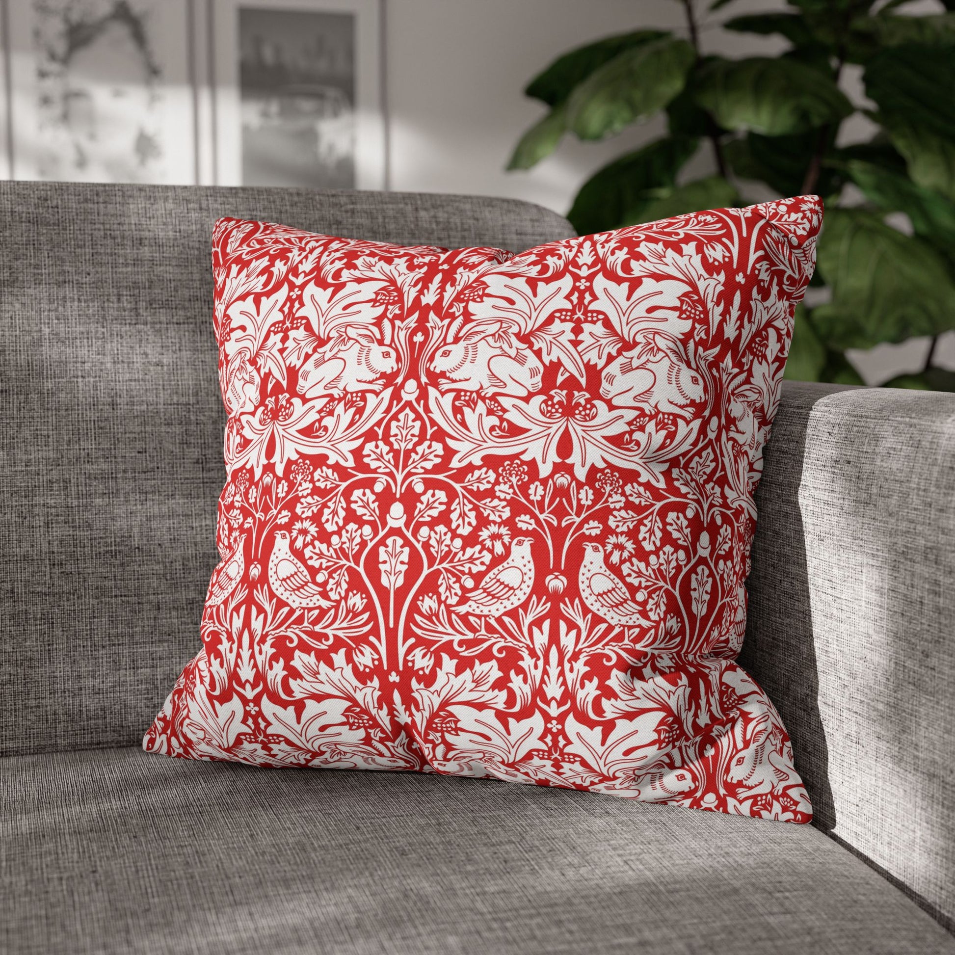 Red and white patterned pillow on a gray sofa with a blurred plant in the background