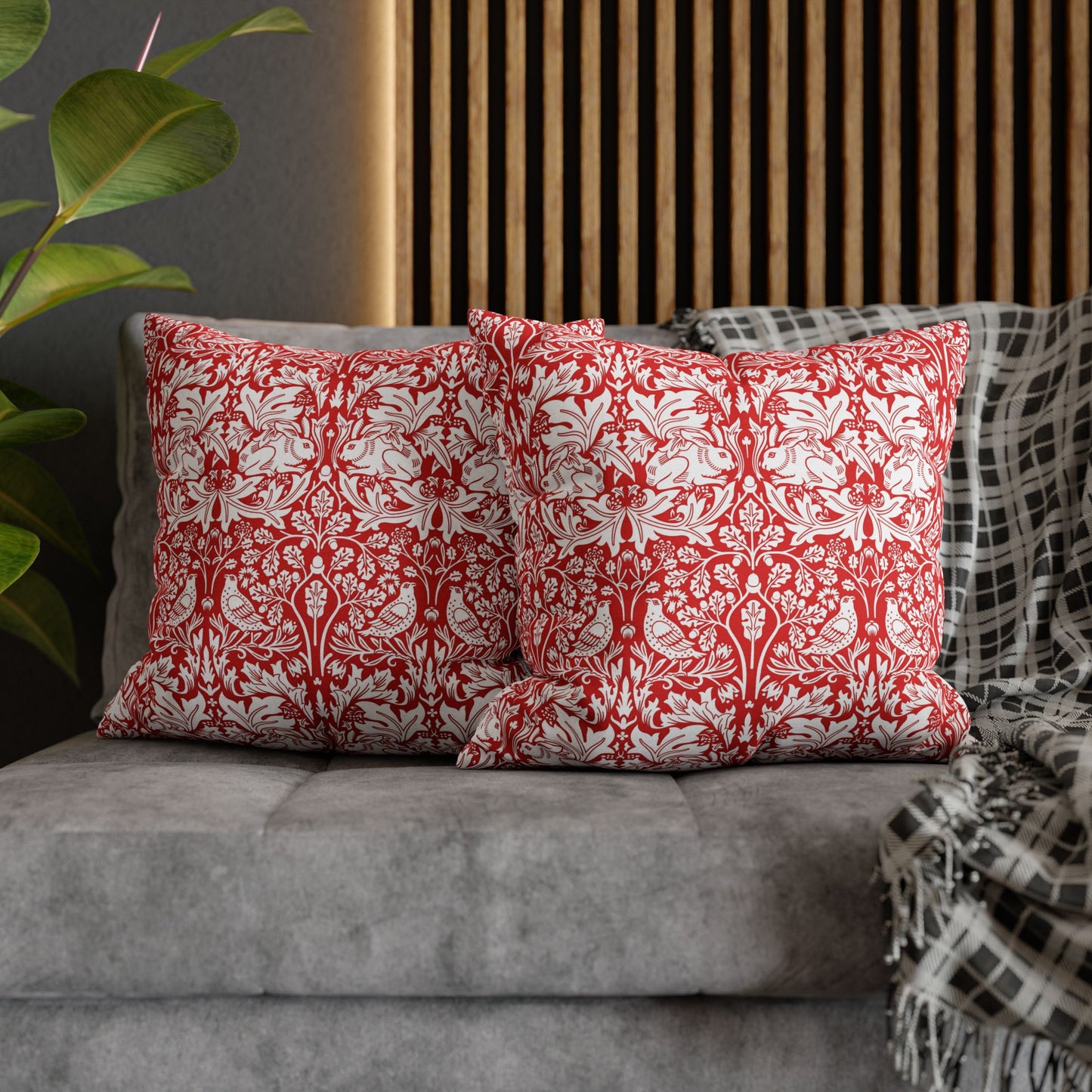 Red and white patterned pillows on a gray sofa with a plant in the background