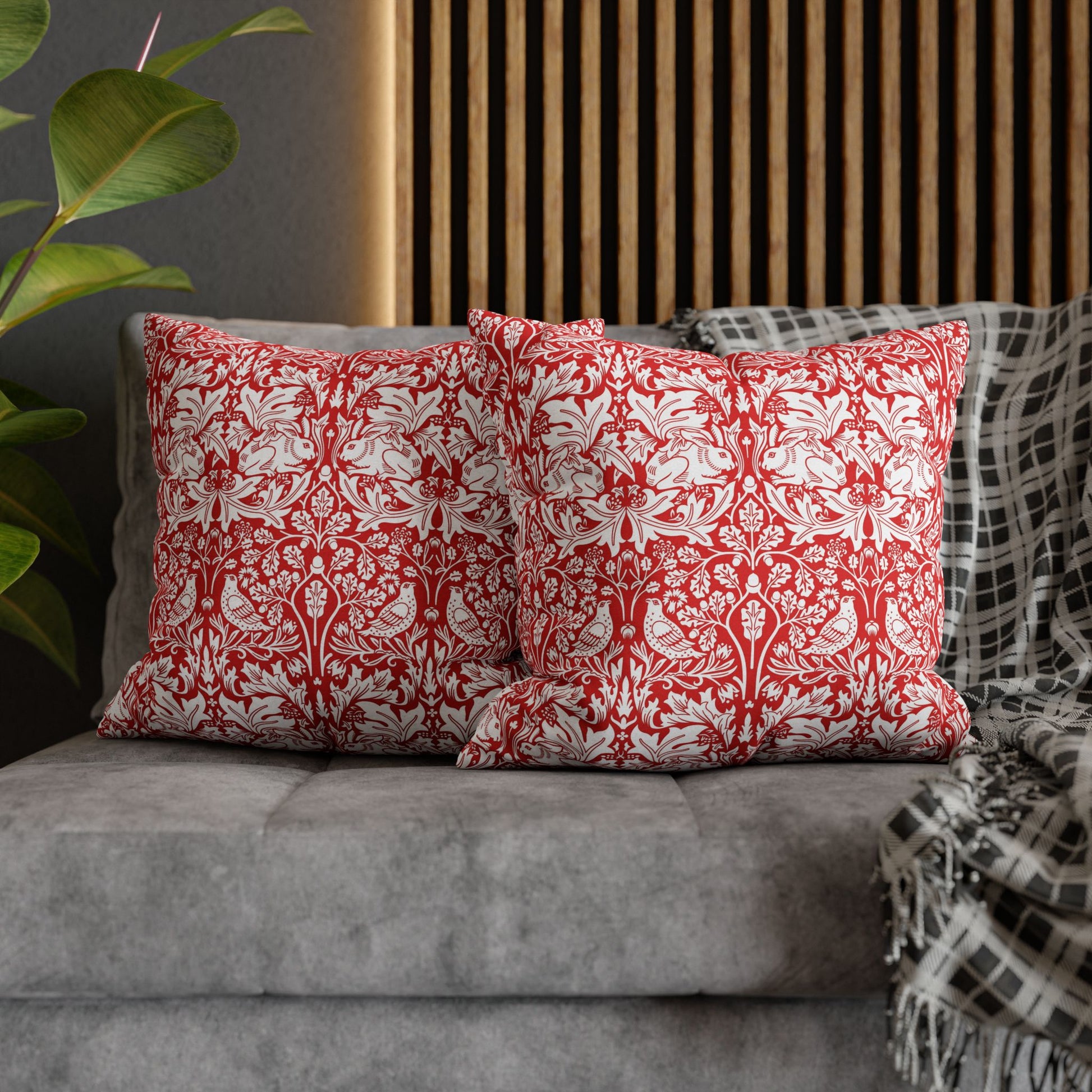 Red and white patterned pillows on a gray sofa with a plant in the background