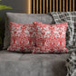Red and white patterned pillows on a gray sofa with a wooden headboard in the background.