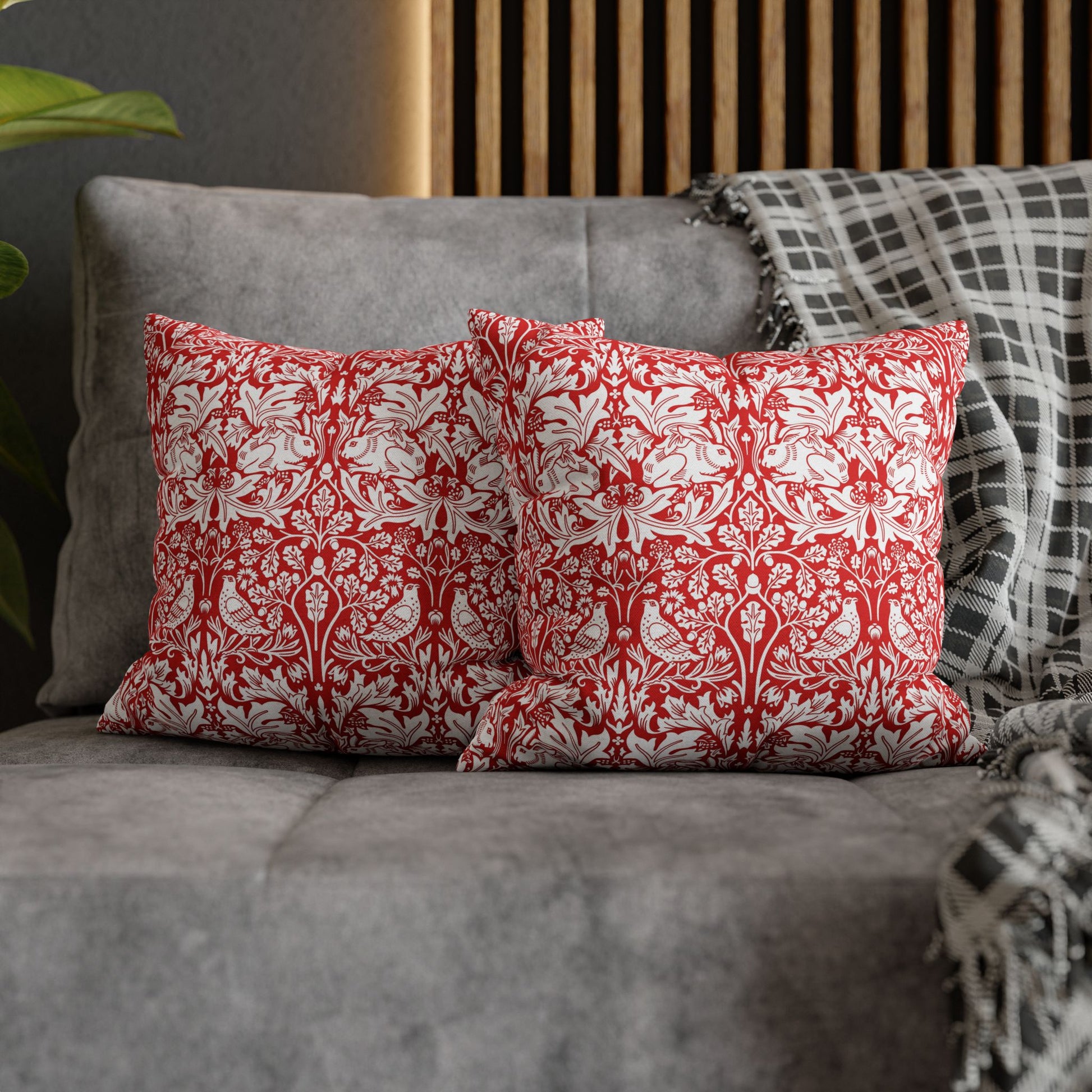 Red and white patterned pillows on a gray sofa with a wooden headboard in the background.