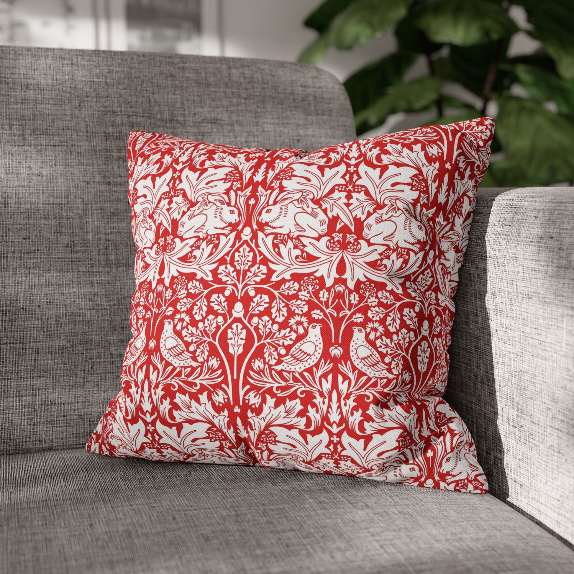 Red and white patterned pillow on a gray sofa with a blurred plant in the background