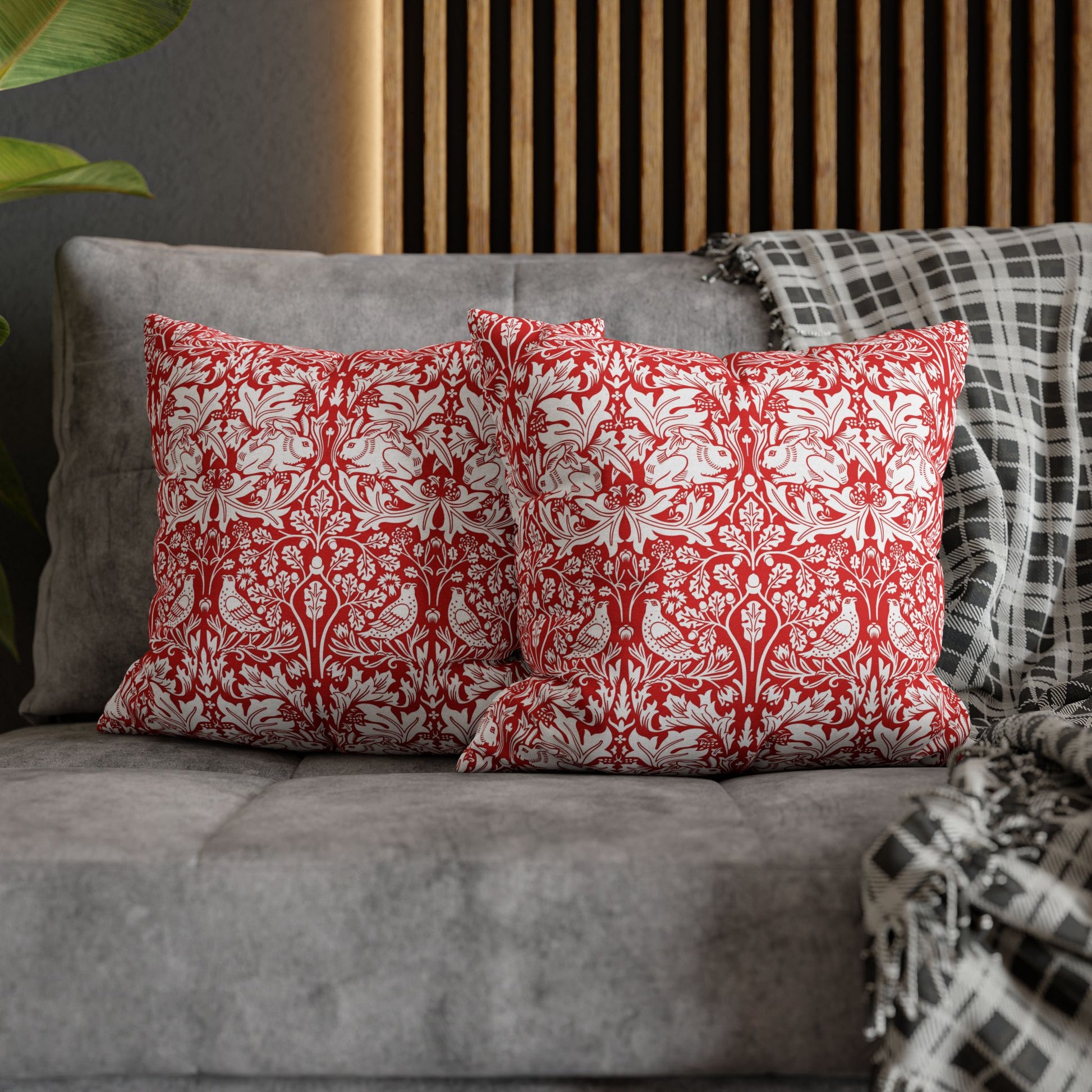 Red and white patterned pillows on a gray sofa with a wooden headboard in the background.