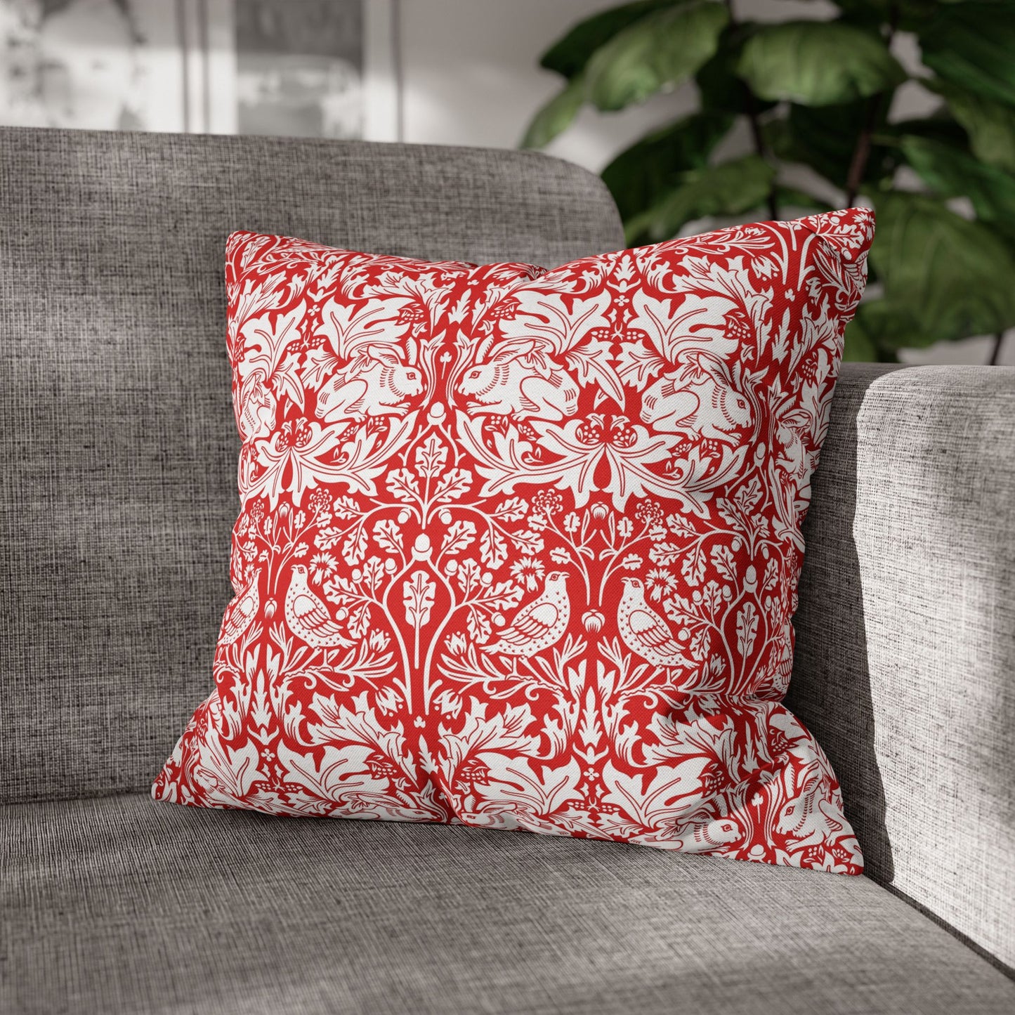 Red and white patterned pillow on a gray sofa with a blurred plant in the background